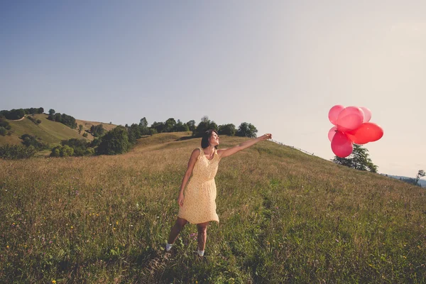 Voksen smuk pige leger med røde balloner - Stock-foto
