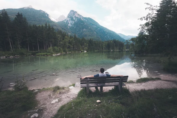 男人坐在附近山上的湖 — 图库照片