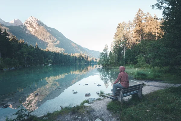 男人坐在附近山上的湖 — 图库照片