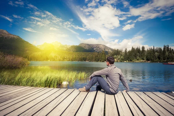 男人坐在高山湖附近 — 图库照片