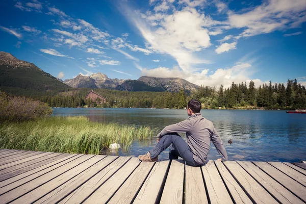 男人坐在高山湖附近 — 图库照片
