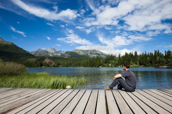 Mann sitzt am Ufer des alpinen Bergsees — Stockfoto