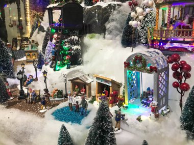 Yeni yıl manzarası. Gösteri için oyuncak minyatür. Güzel bir vitrin, el yapımı kompozisyon. Merkezde alışılmadık bir beyaz hasır çardak var. Yanında yuvarlak meyveli bir meyve ağacı var.