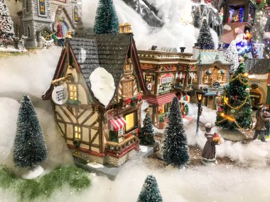 Yeni yıl manzarası. Karların altındaki evler, Noel ağaçları ve çatılı evler. Bahçedeki köknar dalları. Yılbaşı ağaçları altın çelenkler ve toplarla süslenir..