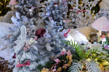 Kış ormanındaki karla kaplı bir ağaçta, ışıkların arkasındaki bir Noel oyuncağının yakın çekimi..