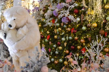 Dükkan dekorasyonu, alışveriş merkezi dekorasyonu. Çelenkli yapay beyaz ladin. Yanlarında oyuncak bir kutup ayısı bir ayı yavrusuna sarılıyor. Şirin Noel manzarası.