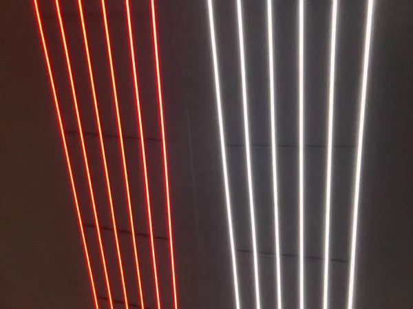 Blurred, no focused, abstract festive vertical background with red, orange and white neon led stripes on a black background, photography for creative workspace for design.