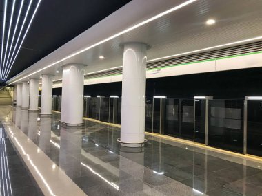 Güvenliği artırılmış metro. Kapısı açılmayan yeni metro istasyonları. Çifte güvenlik, trene girmeden önce otomatik kapılar. Metro istasyonundaki büyük beyaz sütunlar.