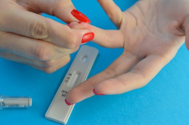 Koronavirüs teşhisi için kan testi. Kız parmağını kendisi için deldi ve parmağındaki kanı sıktı. Koronavirüs teşhisi için kılcal kan örneği..