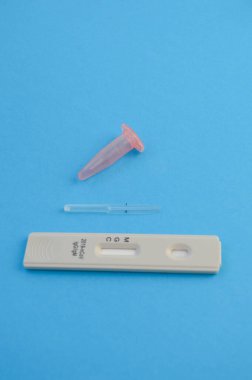 Mavi bir arka planda koronavirüs enfeksiyonunu tespit etmek için test şeridi. Koronavirüs için kan testi. Testin yanında, kan toplamak için bir neşter ve bir pipet var..