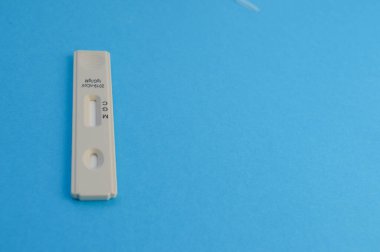Coronavirüs enfeksiyonu teşhisi için beyaz test şeridi. mavi arka planda bir test. Hastalığın teşhisi için bireysel kitler. IgG ve IgM antikorlarının belirlenmesi.