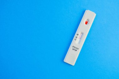 Coronavirus testi mavi arka planda yatar. Test şeridinde bir damla venöz kan. Tıbbi laboratuvar, koronavirüs teşhisi. Test IgG ve IgM antikorlarının varlığını gösteriyor..