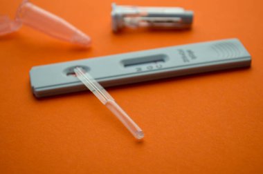 Turuncu arka planda koronavirüs testi. Bir mat arka planında, koronavirüs için hassas bir şerit, bir mızrak, salin için bir kap. Coronavirus için test kiti.