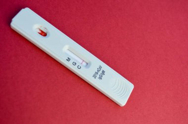 Coronavirus testi kırmızı arka planda yatar. Enfeksiyonu belirlemek için parlak bir arka planda beyaz test şeridi. Koronavirüs antikorları için hassas test.