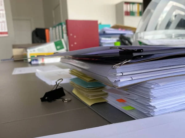 Çalışma masasında, kırtasiye ve aksesuarları olan önemli kağıt ve belgelere sahip büyük kalın klasörler..