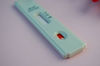 Koronavirüs testi pembe arka planda yatar. Testte bir damla kan vardı. IgG ve IgM sınıflarının antikorlarının belirlenmesi için test edin. ev sağlık durumunun teşhisi.
