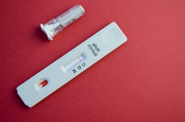 Coronavirus testi kırmızı arka planda yatar. Koronavirüs antikorları için hassas bir test. Yanında bir parmağın delinmesi için beyaz bir mızrak var. Antikorların tespiti için kan.