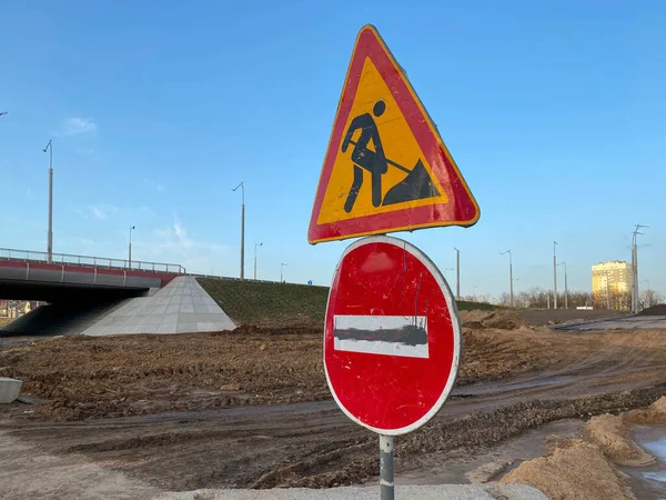 Under construction board sign on the closed road with arrow sign and traffic cone. Caution symbol under construction, work in progress sign.