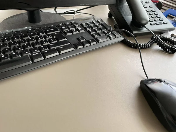 Black modern computer mouse keyboard and telephone on a working office table in a business company.