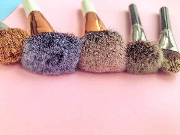 Set of different makeup brushes, makeup tools on pastel blue and beige pink background.