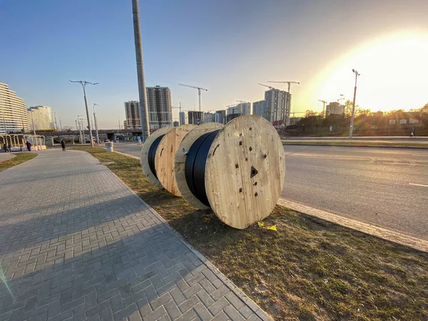 Elektrik kablosu ile yuvarlak ahşap şiş. Kablo büyük, tahta bir makaraya sarılı. İnşaat alanı, yeraltında yatan kablolar bölgeye elektrik sağlıyor..