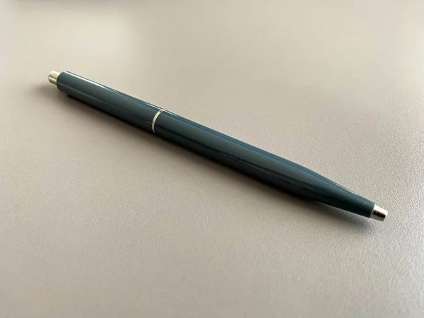 Automatic green ballpoint pen for writing on your desktop office desk. Business work.