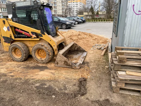 Mini excavator digging earth in a field or forest. Laying underground sewer pipes during the construction of a house. Digging trenches for a gas pipeline or oil pipeline. Earthwork, foundation pit.