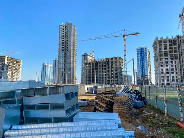 Laying concrete sewer wells and sewer pipes. Sewage drainage system for a multi-story buildings. Tower cranes in action at a construction site. Building the homes.