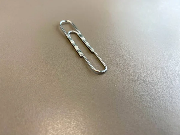 Shiny metal paper clips on a desktop with stationery in a business office. Close view.