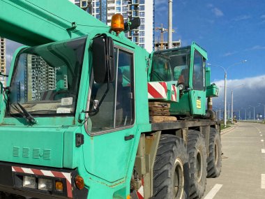 Şehrin yeni alanlarının yapımında kullanılan büyük, güçlü, endüstriyel, yeşil bir vinç. Özel inşaat ekipmanları.