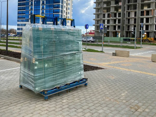 A large package of glass for windows of double-glazed windows wrapped with stretch film on the working site during the construction of houses.