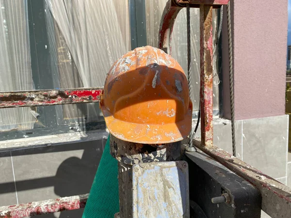 Yellow plastic protective dirty scratched old construction worker\'s helmet to protect head from falling objects at construction site.