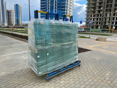İnşaat sırasında çalışma alanına streç film sarılı çift camlı pencereler için büyük bir paket cam..
