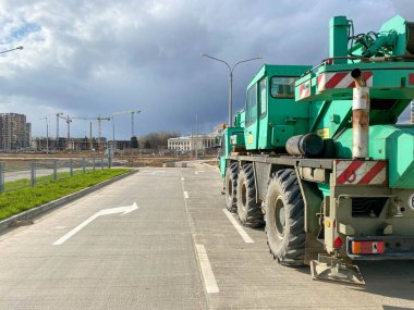 Şehrin yeni alanlarının yapımında kullanılan büyük, güçlü, endüstriyel, yeşil bir vinç. Özel inşaat ekipmanları.
