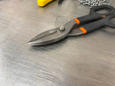 Demir gibi keskin metal makas, metal makaslar demir bir masanın üzerinde yatar. El yapımı çilingir aletleri. Arkaplan.
