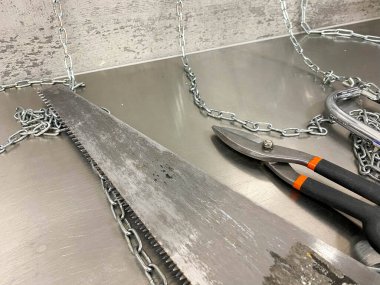 Demir gibi keskin bir makas, metal kesiciler ve demir bir masanın üzerinde zincirli bir testere. El yapımı çilingir aletleri. Arkaplan.