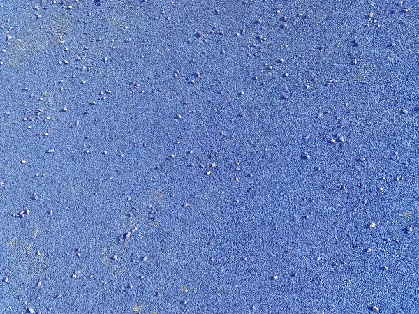 The blue texture of the soft rubber surface of the safe cover of the sports playground for workout made of pressed fine rubber. The background. Texture.