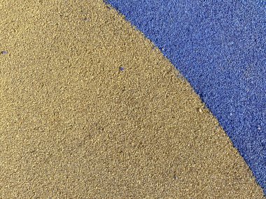 Spor parkının güvenli kapağının yumuşak lastik yüzeyinin mavi ve sarı dokusu baskılı kauçuktan yapılmış egzersiz için. Arka plan. Doku.