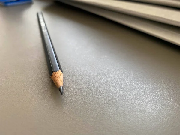 A simple black pencil lies sharply sharpened next to folders with sheets of paper and documents on the working business desk in the office. Stationery.