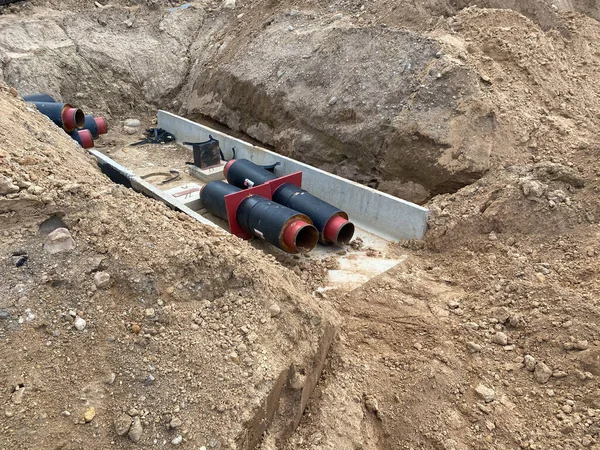 Pipes in trench, industrial pipeline. Insulated pipes to connect a new buildings on heat system. One insulated pipe carries hot water, another carries cool water.