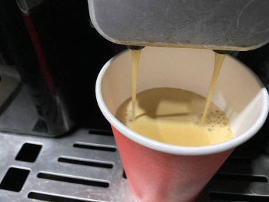 Kahve makinesi bardaki sarı karton kahve fincanına kahve dolduruyor. Kesilmiş görüntü. Yakın çekim..