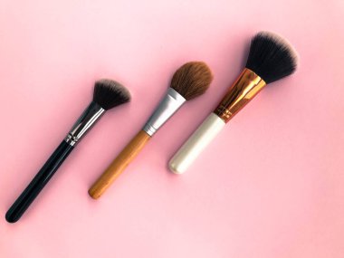 Pembe bir arka planda üç püskül. Kızarma, toz, temel ve dış hatlar için kuru dokular için fırçalar. Yüz makyajı. kişisel bakım, güzellik ve moda.