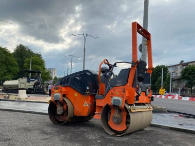 Küçük asfalt patenci asfalt yolu tamir ederken görev başında. Yol yapımı, sanayi ve takım çalışması üzerine çalışan işçiler.