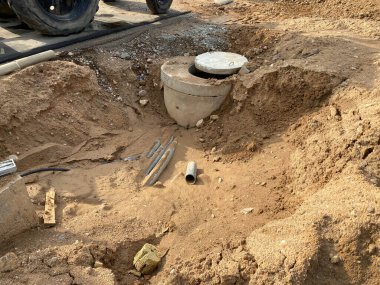 İnşaat alanındaki bir çukurda beton rögar deliği. Kanalizasyon mühendisliği ağlarının endüstriyel inşaatı.