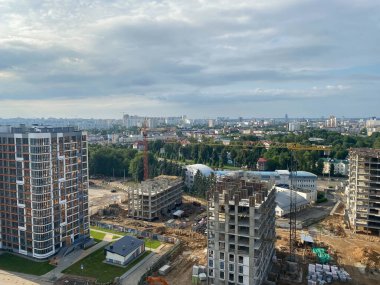 Yüksek büyük evler ve çok katlı binalardan oluşan büyük ve modern bir inşaat alanının manzarası. Büyük bir şehirde yeni bir küçük bölgenin inşaatı için bir şantiye..