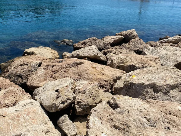 蓝色温暖的大海沙滩上的砂岩岩石 — 图库照片