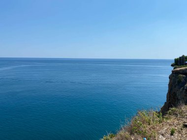 Tropikal adada çimen ve deniz dalgaları olan güzel kumlu bir uçurum. Okyanus koyunda ya da gölde büyük kaya ve dalgalar.