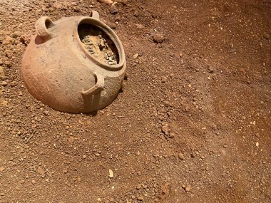 Beyaz kumun üzerinde bir Yunan kil tenceresi yatıyor. Kumsalda beyaz kum. Topraktan yapılmış tabaklar, üst görünüm.