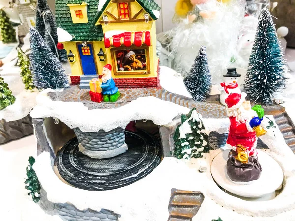 Yeni yıl manzarası. Gösteri için oyuncak minyatür. Çok katmanlı kompozisyon. Merkezde oyuncak bebekler için kırmızı bir atlıkarınca var. Noel için dekorasyonlar.