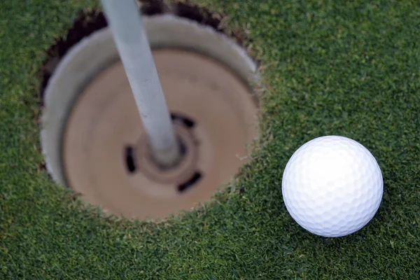 Bola de golfe perto de buraco — Fotografia de Stock
